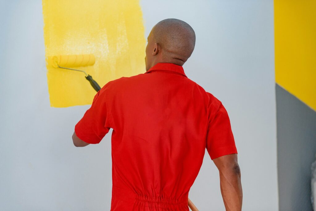 Painter rolling white paint onto a wall with a roller